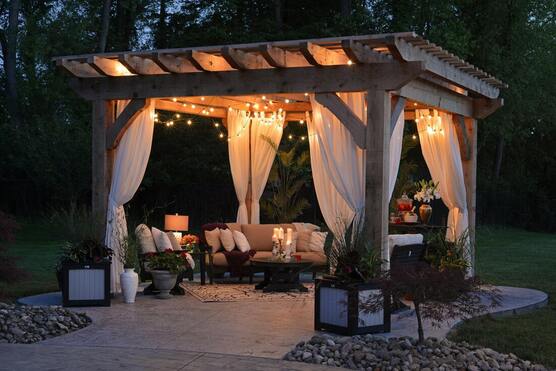 Lit up pergola outside at night staged with nice patio furniture